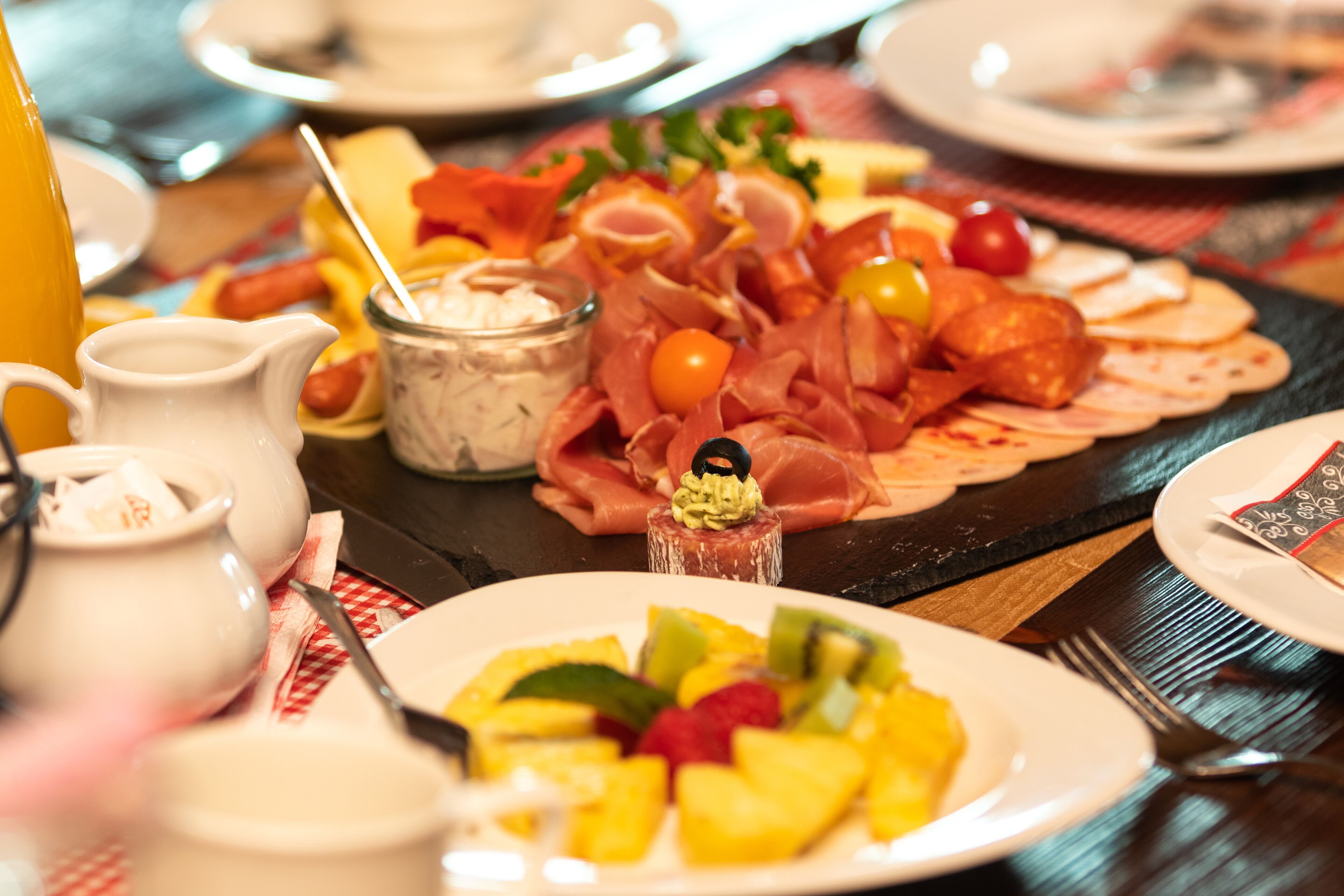 A table set with various food items including a fruit platter, a cheese board, and a selection of meats.