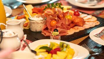 A table set with various food items including a fruit platter, a cheese board, and a selection of meats.