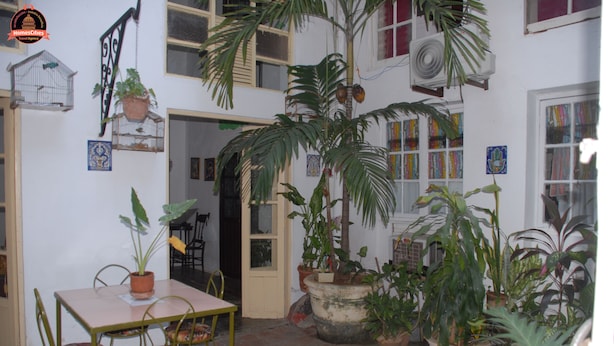 A courtyard with a table and chairs, surrounded by potted plants and a birdcage. - Alameda dePaula (Havana)