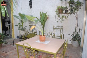 A patio with a table and chairs, surrounded by potted plants and a white wall. - Alameda dePaula (Havana)