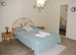Une chambre à coucher comprenant un lit, une table de chevet, un miroir et des œuvres d’art décoratives au mur.