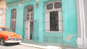 A teal building with ornate metal gates and a vintage car parked in front. - Alameda dePaula (Havana)
