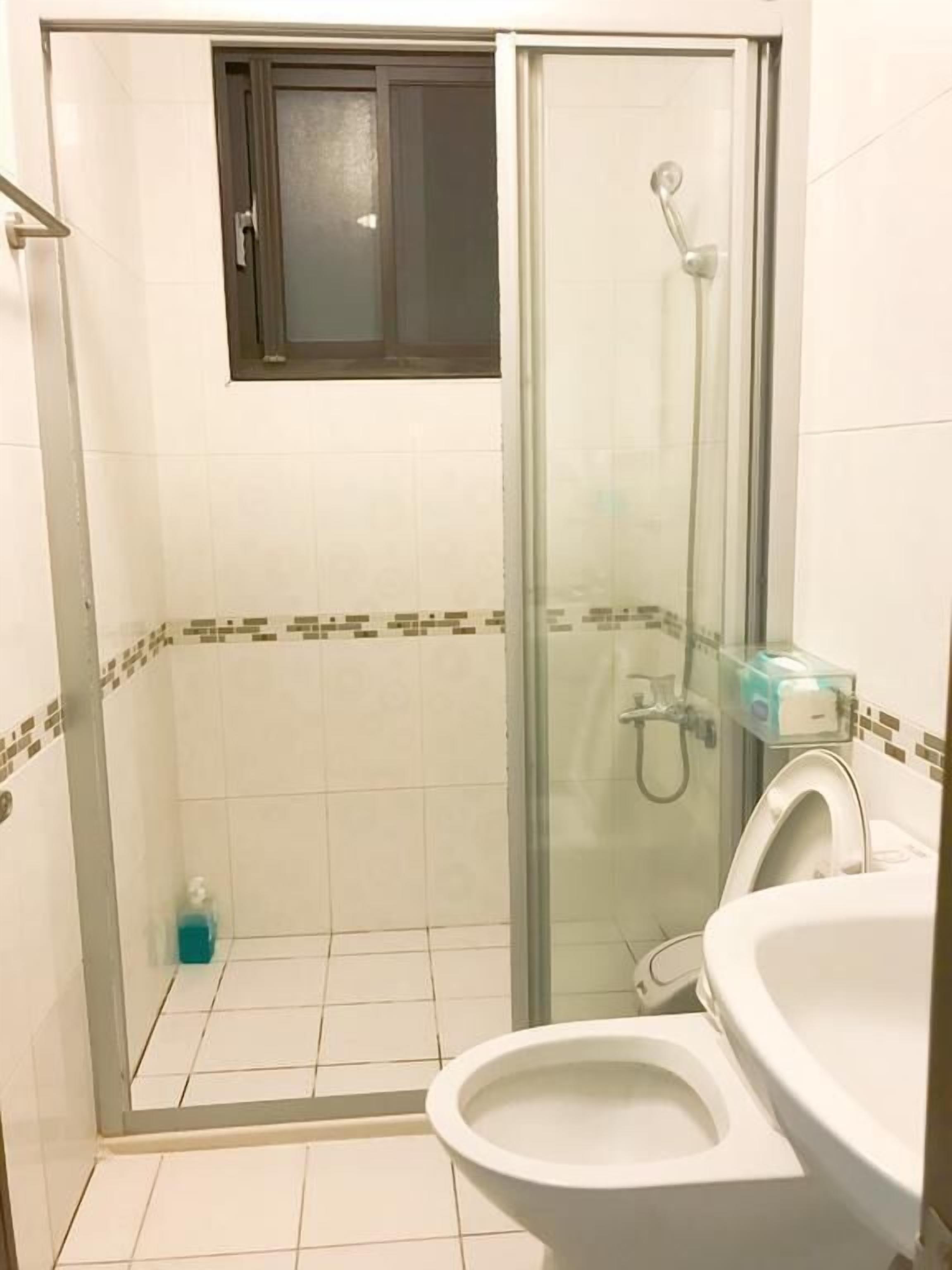 A bathroom with a glass-enclosed shower, a toilet, and a sink.