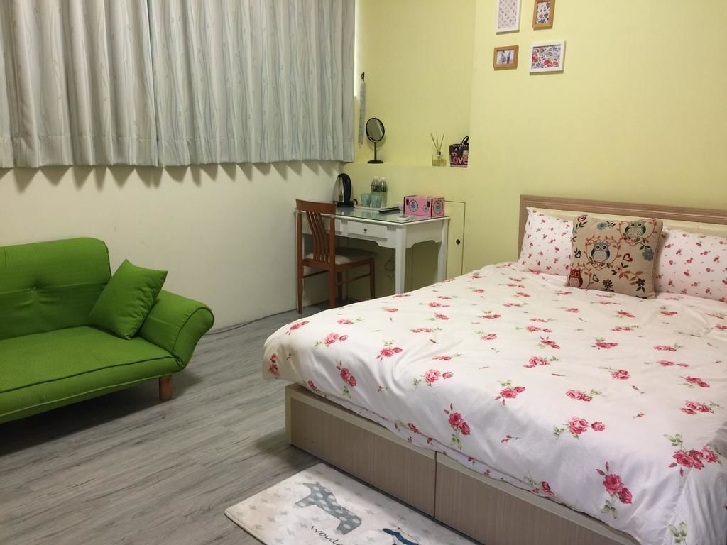 Un dormitorio con una cama, un sofá verde, un escritorio y una silla.