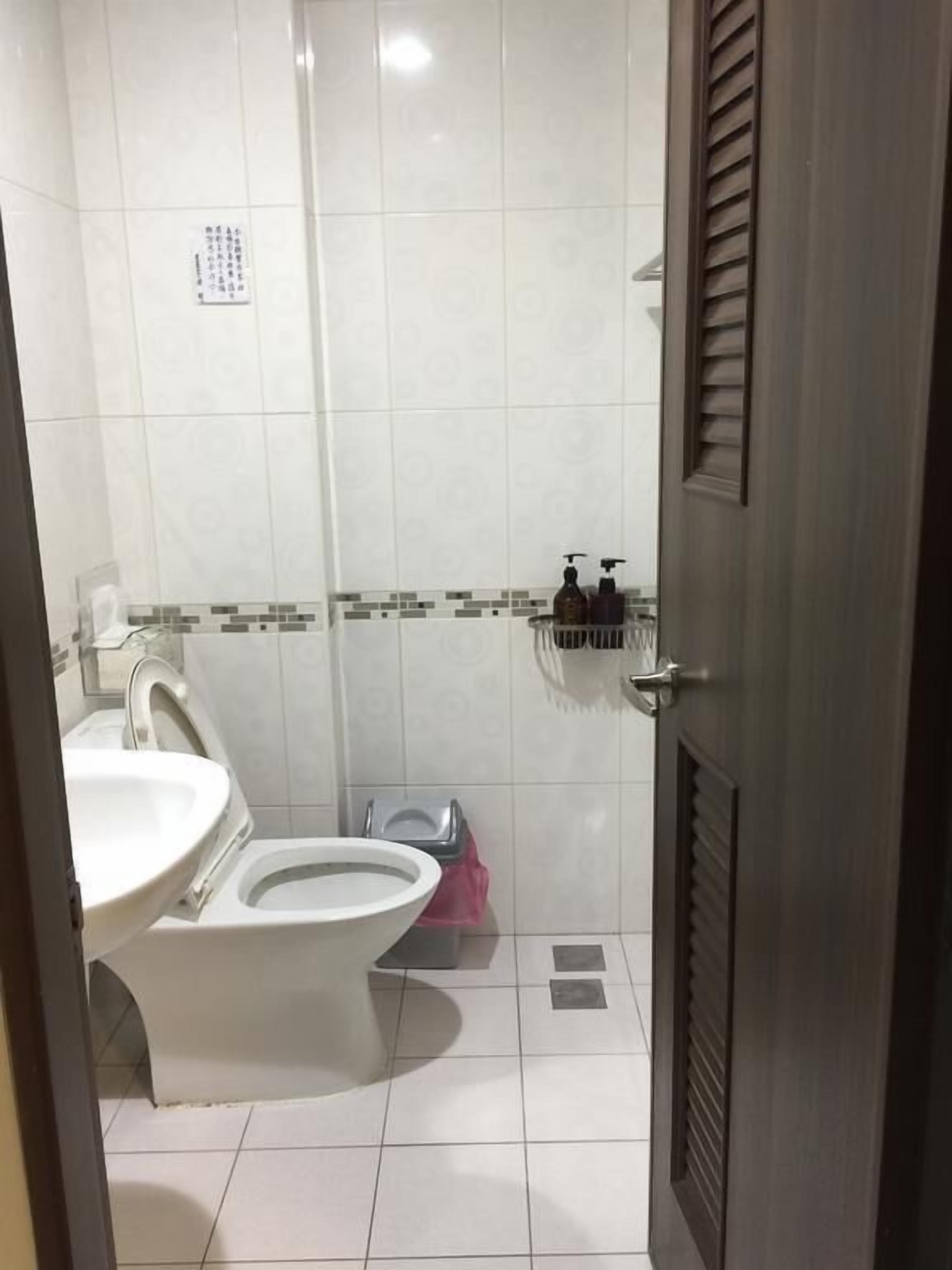 A bathroom with a toilet, sink, and shower area.