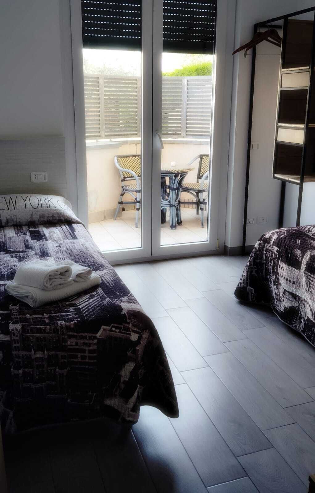 A bedroom with a bed, a chair, and a view of the outside.