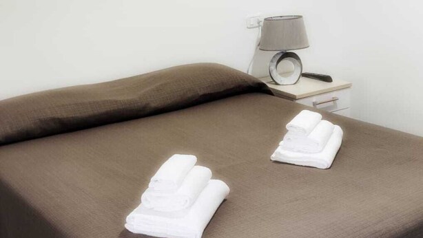 Una habitación de hotel con cama, lámpara y un cuadro en la pared.