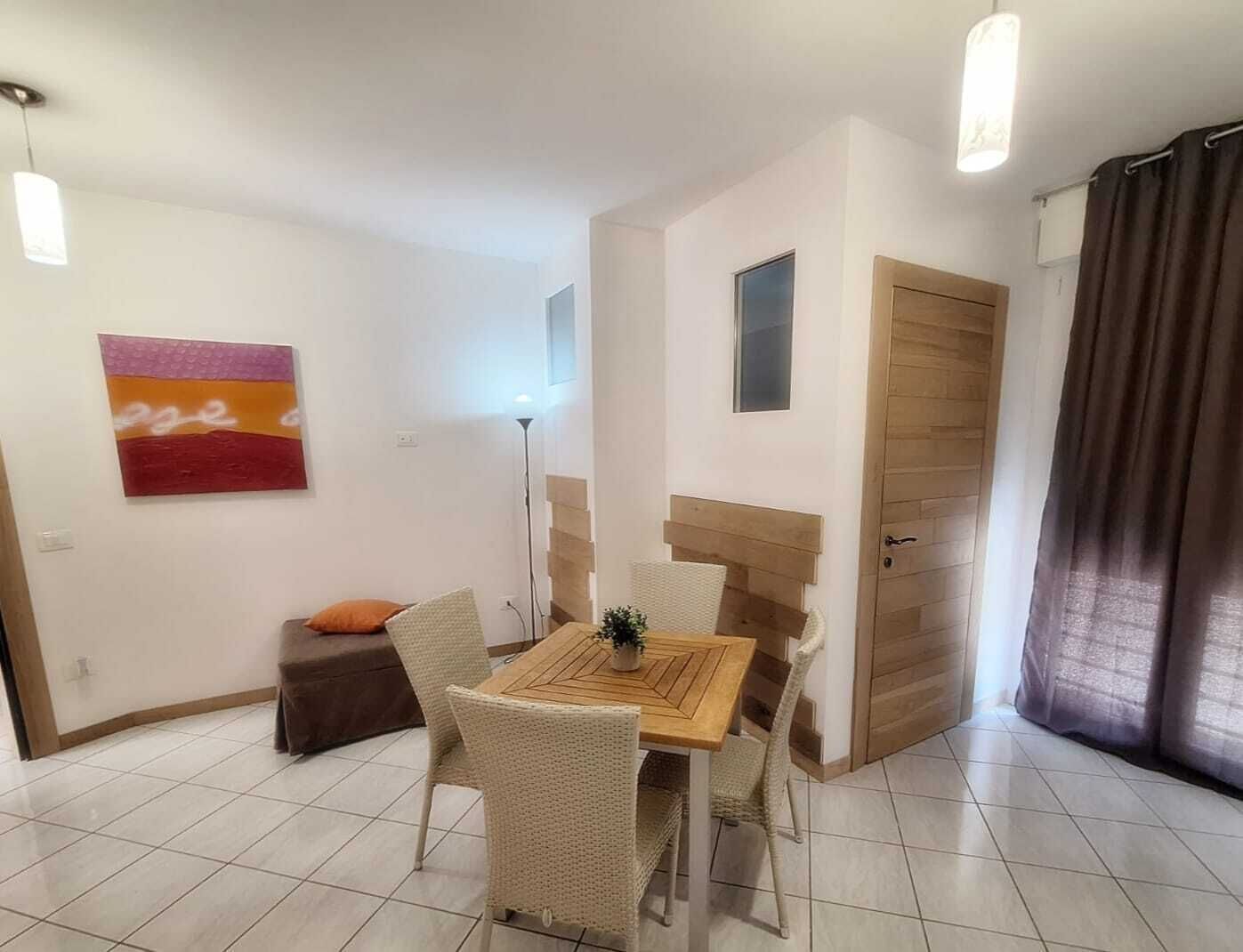 A dining area with a table and chairs, a small wall art piece, a door, and a window.