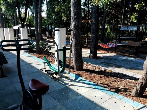 A park with exercise equipment, a hammock, and a paved path.