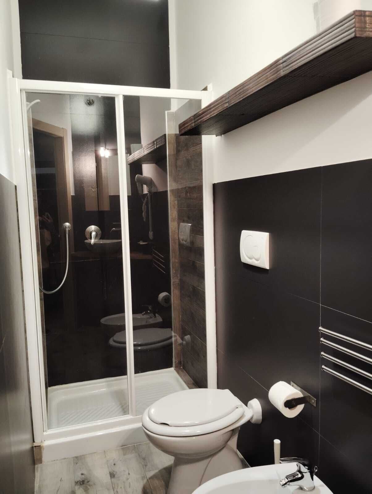 A modern bathroom with a glass shower enclosure, a toilet, and a sink.