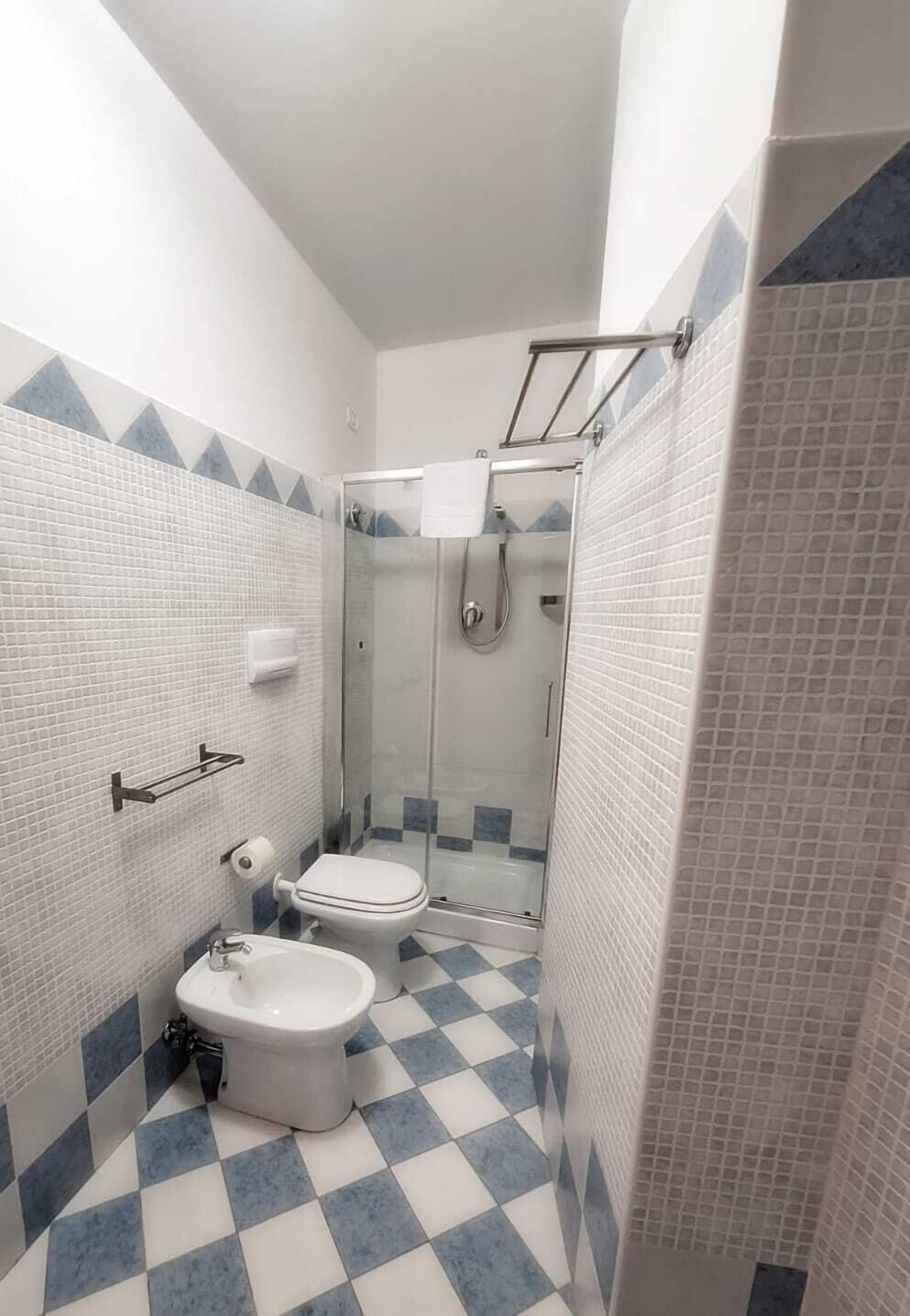 Baño con ducha, inodoro, bidé y piso de baldosas.