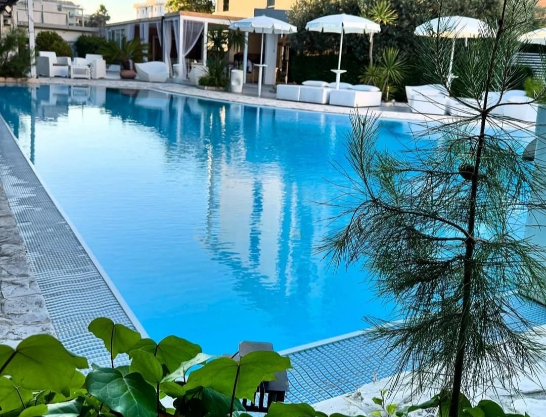 Una piscina con lettini e ombrelloni, immersa nel verde.