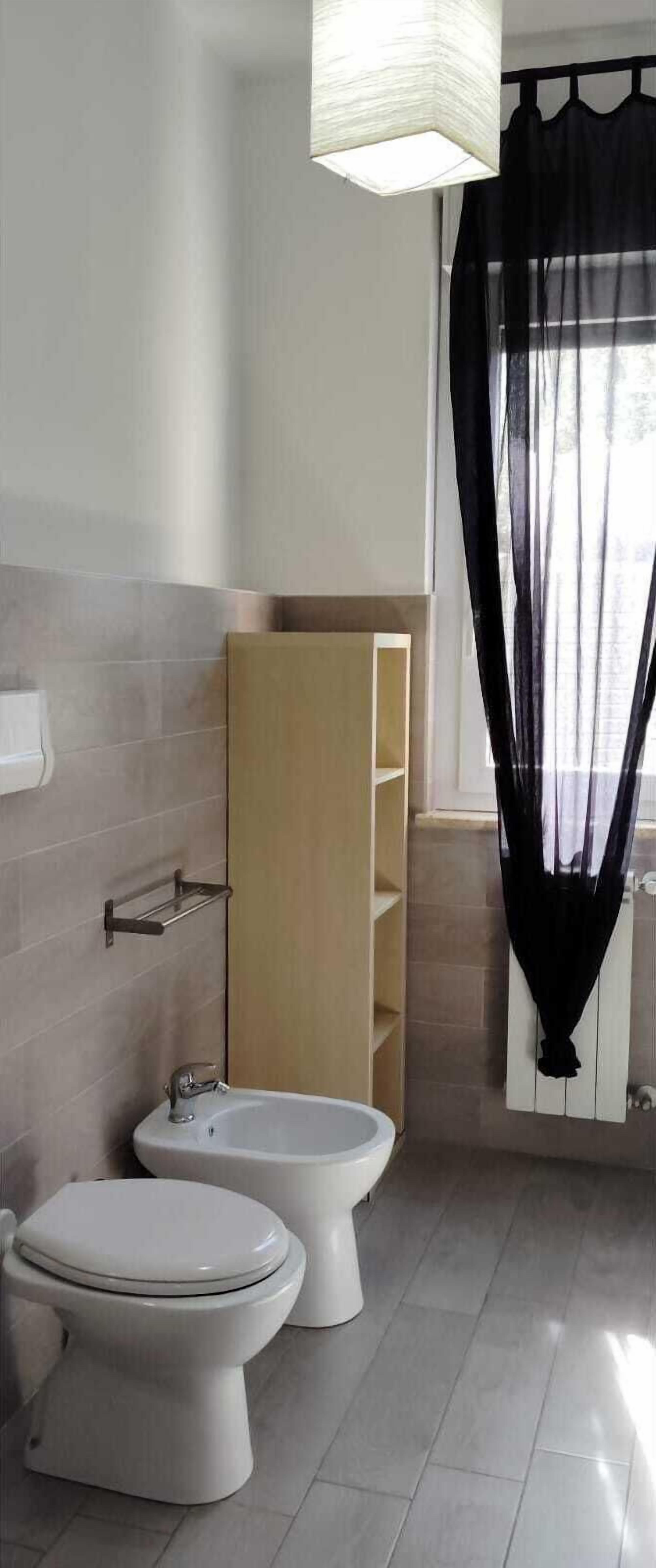 Une salle de bain avec deux toilettes, un bidet, un porte-serviettes et un meuble en bois.