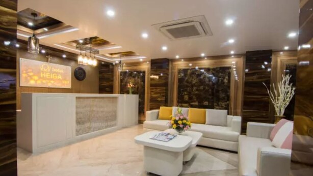 A modern hotel lobby with a reception desk, a sofa, and a coffee table. - Hotel Heiga (Shillong)