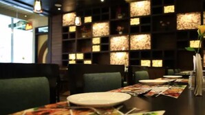 A restaurant interior with tables set for dining, chairs, and a decorative wall with illuminated panels. - Hotel Heiga (Shillong)