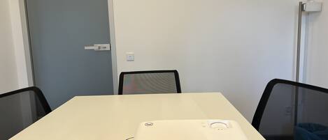 A conference room with a white table, black chairs, and a projector on the table.