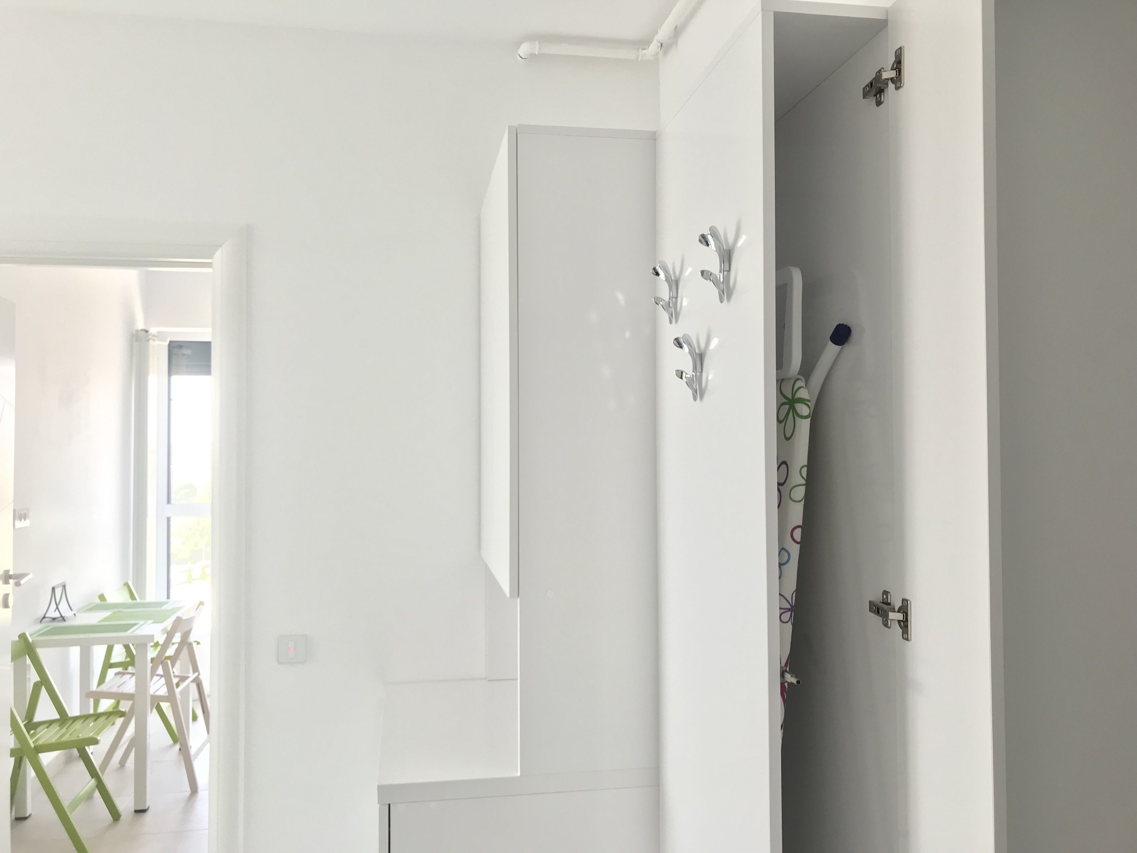 A modern interior with a white wall, a door with a handle, and a small window.