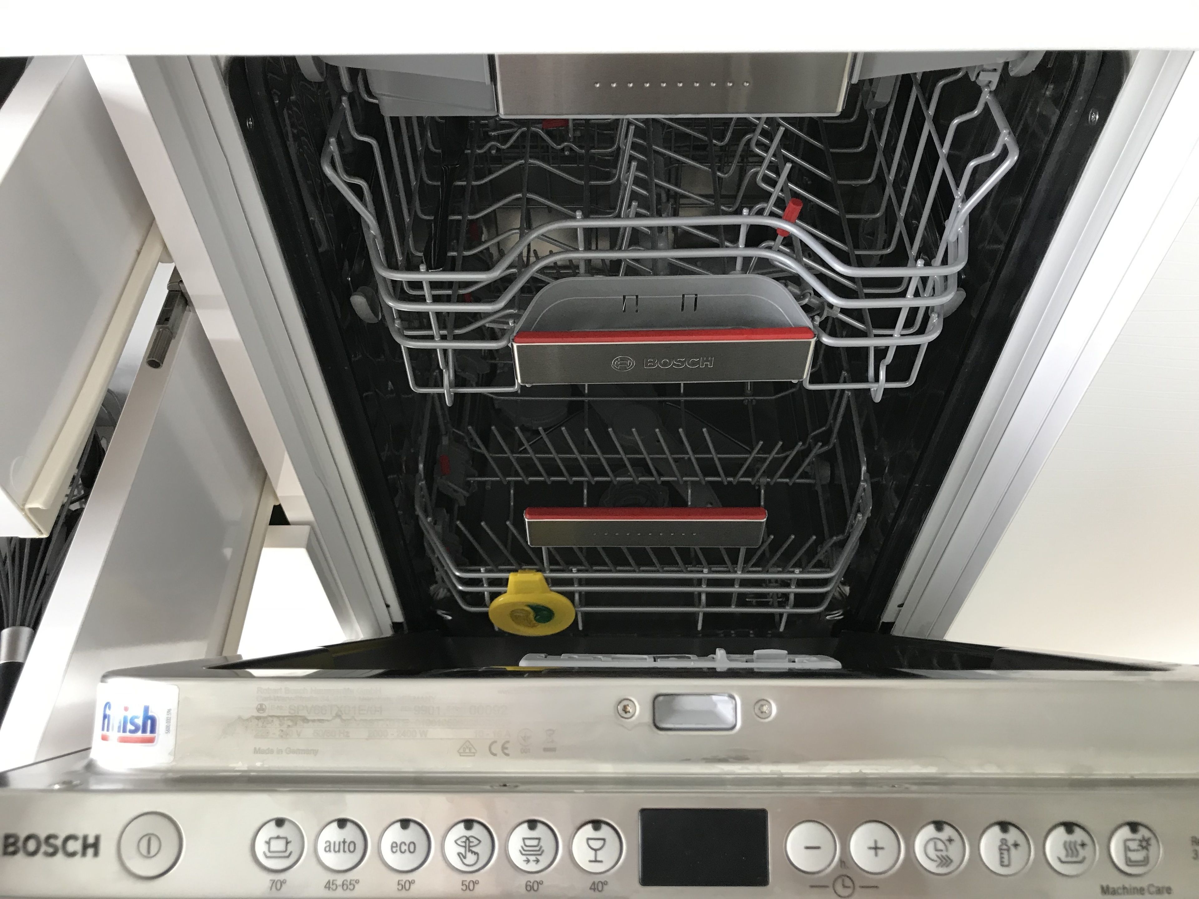 An open Bosch dishwasher with multiple racks and a control panel with various settings.