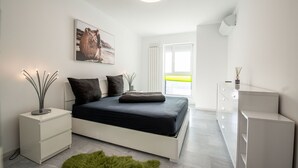 A modern bedroom with a bed, bedside tables, a green rug, a painting, and a window with blinds. - Luxury Westpark 2 Residence Lake View W2 (Bucharest)