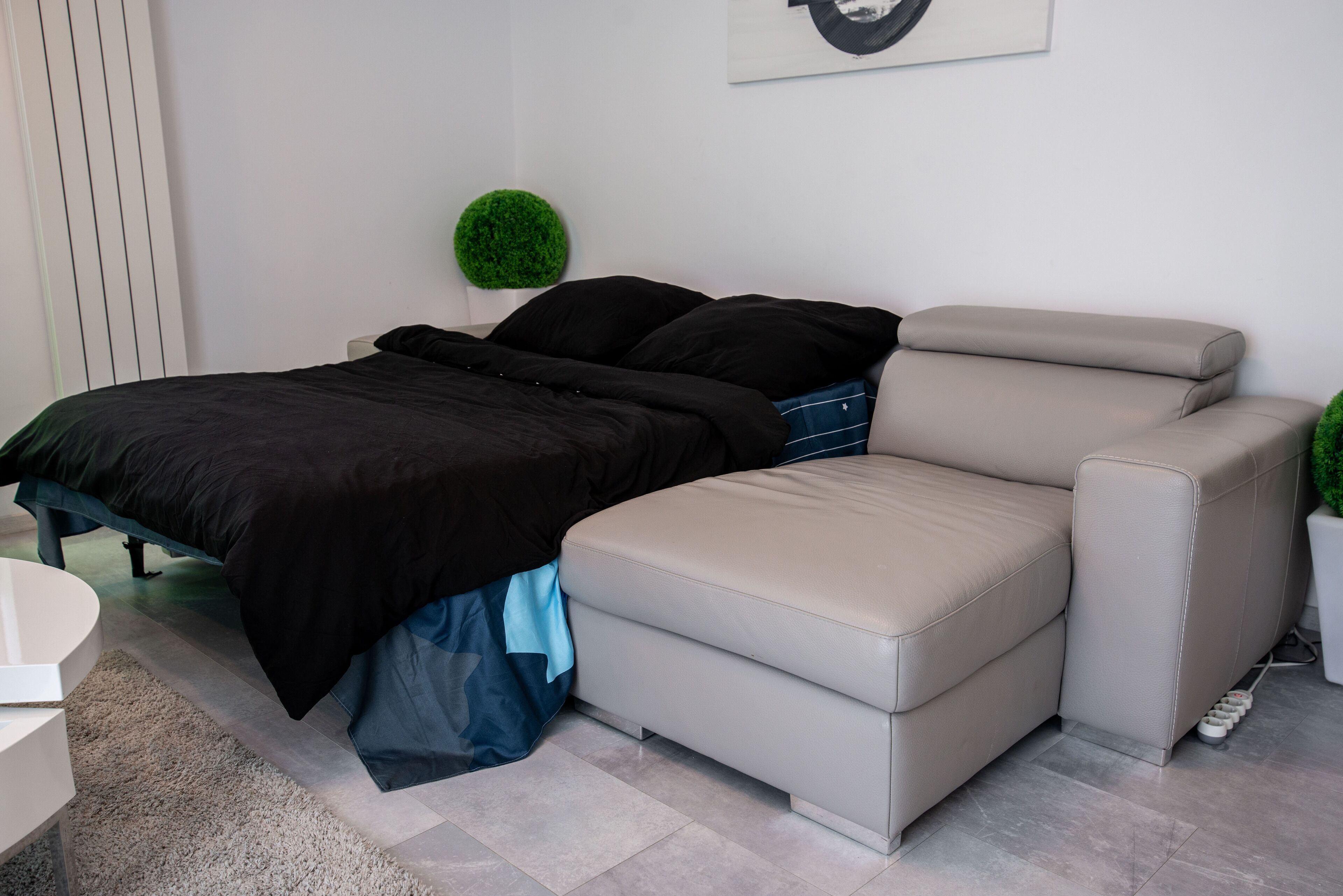 Un dormitorio moderno con cama, sofá, una mesita y un adorno verde en la pared.