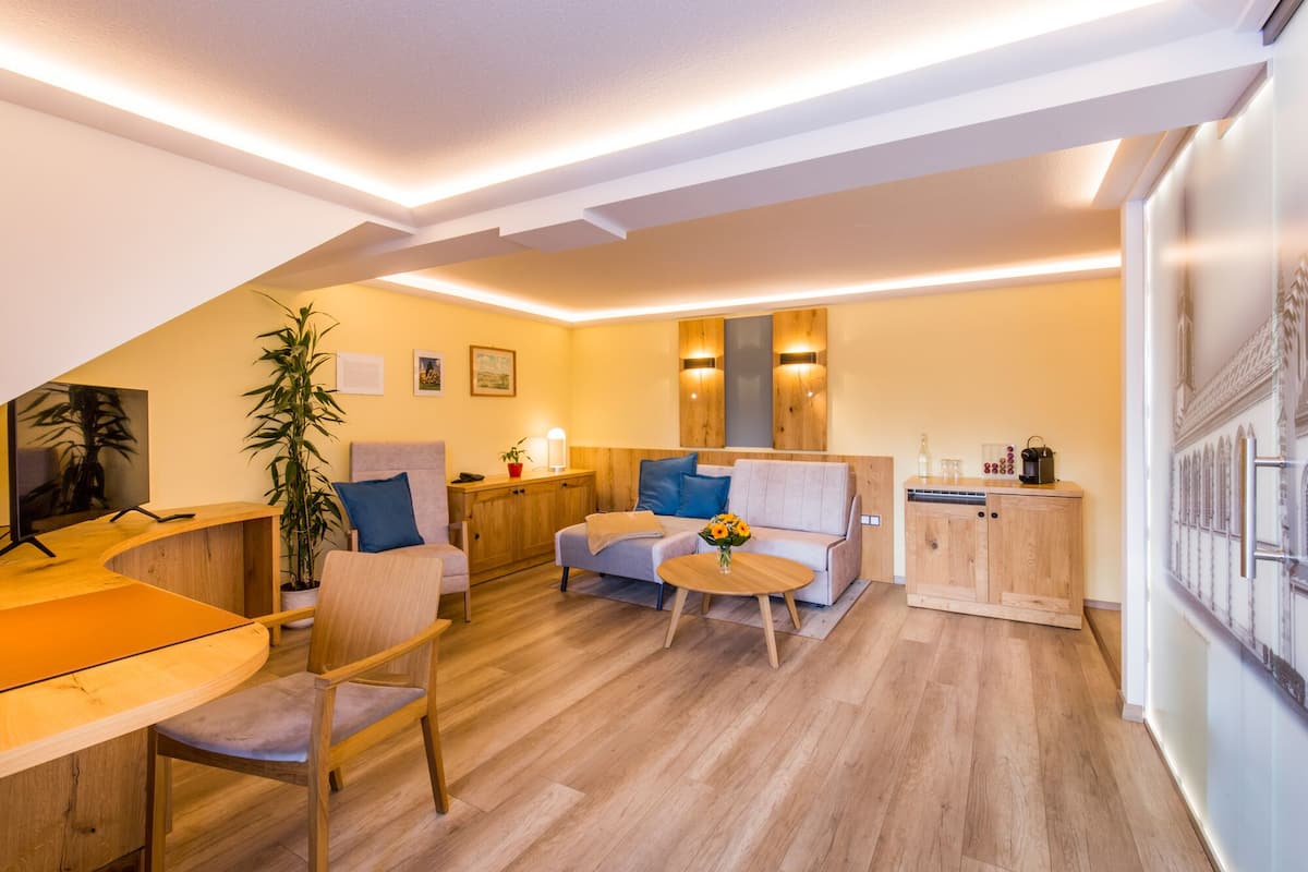 A modern living room with a wooden floor, a sofa, a coffee table, and a dining area with a wooden table and chairs.