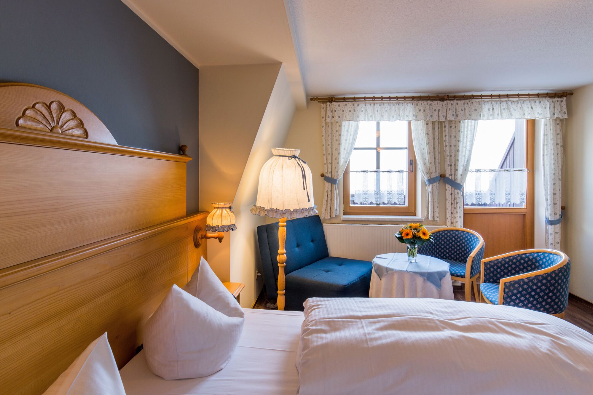 A hotel room with a bed, a desk, a chair, and a window with curtains.