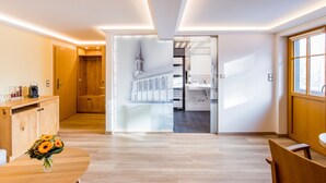 Een moderne hotelkamer met een houten vloer, een houten kast, een bloemenvaas en uitzicht op een kerk door een etalageruit.