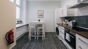 A modern kitchen with a dining area, built-in appliances, and a fire extinguisher. - *Renovated* Dilo Apartments - MyGold - Large 120-square-meter apartment, 2 bedrooms, with a balcony (Berlin)