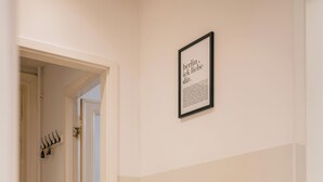 A hallway with a bench, a door, and a framed sign on the wall. - *Renovated* Dilo Apartments - MyGold - Large 120-square-meter apartment, 2 bedrooms, with a balcony (Berlin)