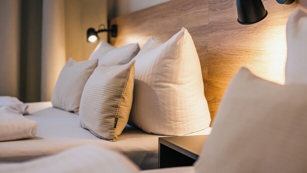 A neatly made bed with pillows, a wooden headboard, and two wall-mounted reading lamps. - *Renovated* Dilo Apartments - MyGold - Large 120-square-meter apartment, 2 bedrooms, with a balcony (Berlin)