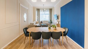 A modern dining area with a round table, six chairs, and a chandelier. - *Renovated* Dilo Apartments - MyGold - Large 120-square-meter apartment, 2 bedrooms, with a balcony (Berlin)
