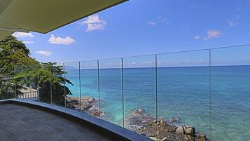 A balcony with a clear view of the ocean and rocky shoreline.