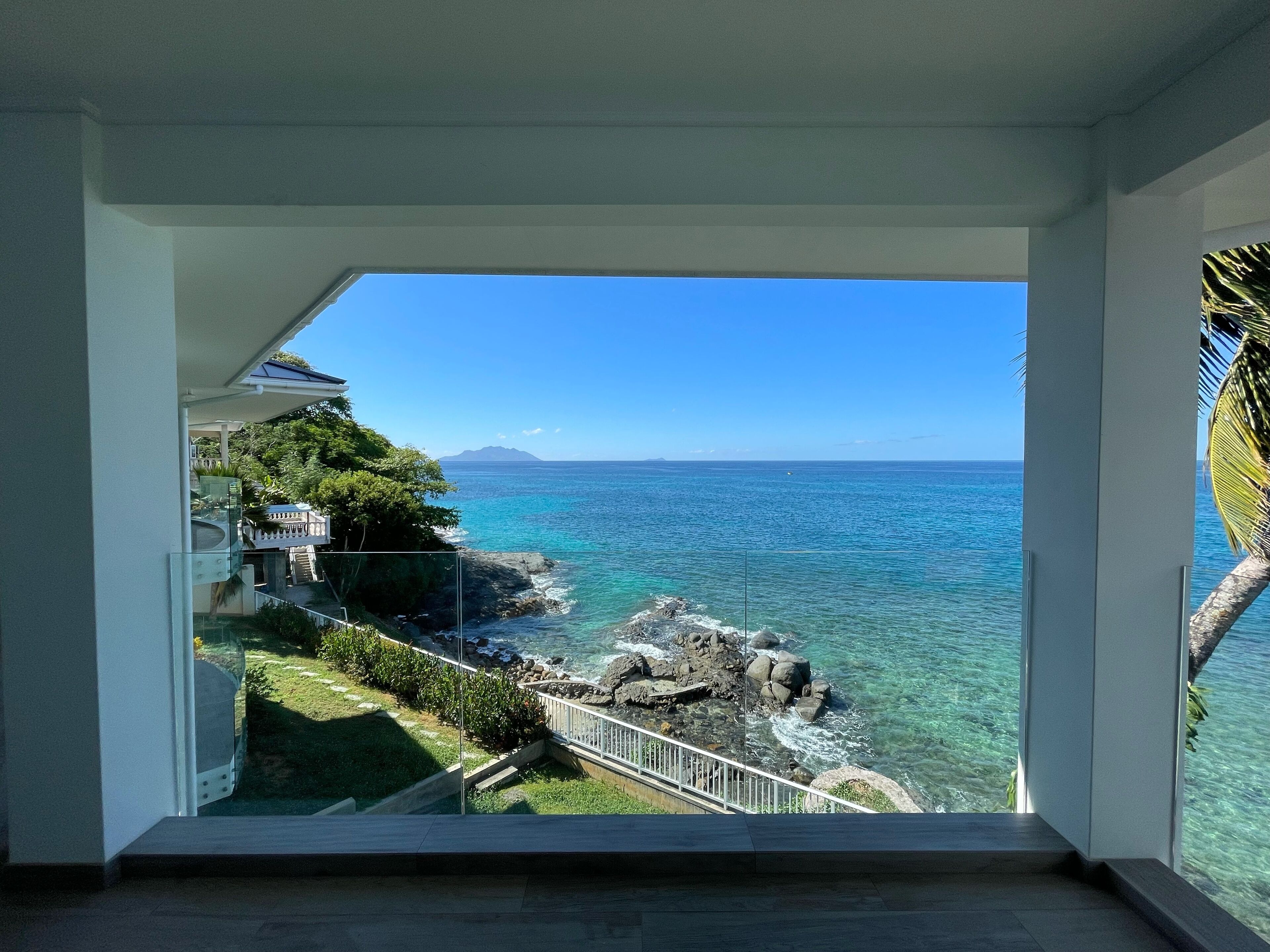 Un balcon offrant une vue dégagée sur l’océan et sur une chaîne de montagnes lointaine.