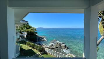 Un balcon offrant une vue dégagée sur l’océan et sur une chaîne de montagnes lointaine.