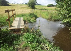 A wooden bench by a calm stream in a grassy field. - Holiday house in the Eifel (Effelsberg)