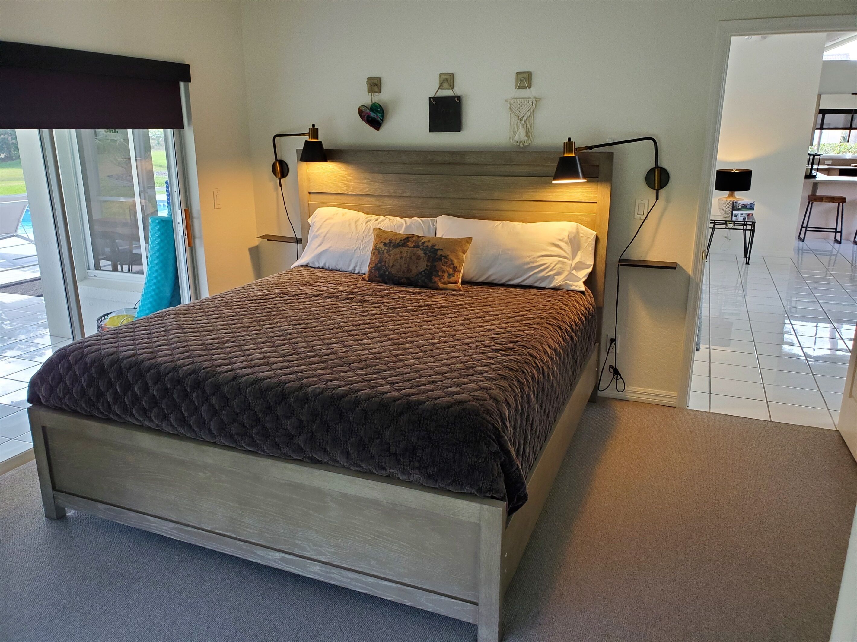 A bedroom with a bed, two bedside lamps, a headboard, and a view of the outdoors.