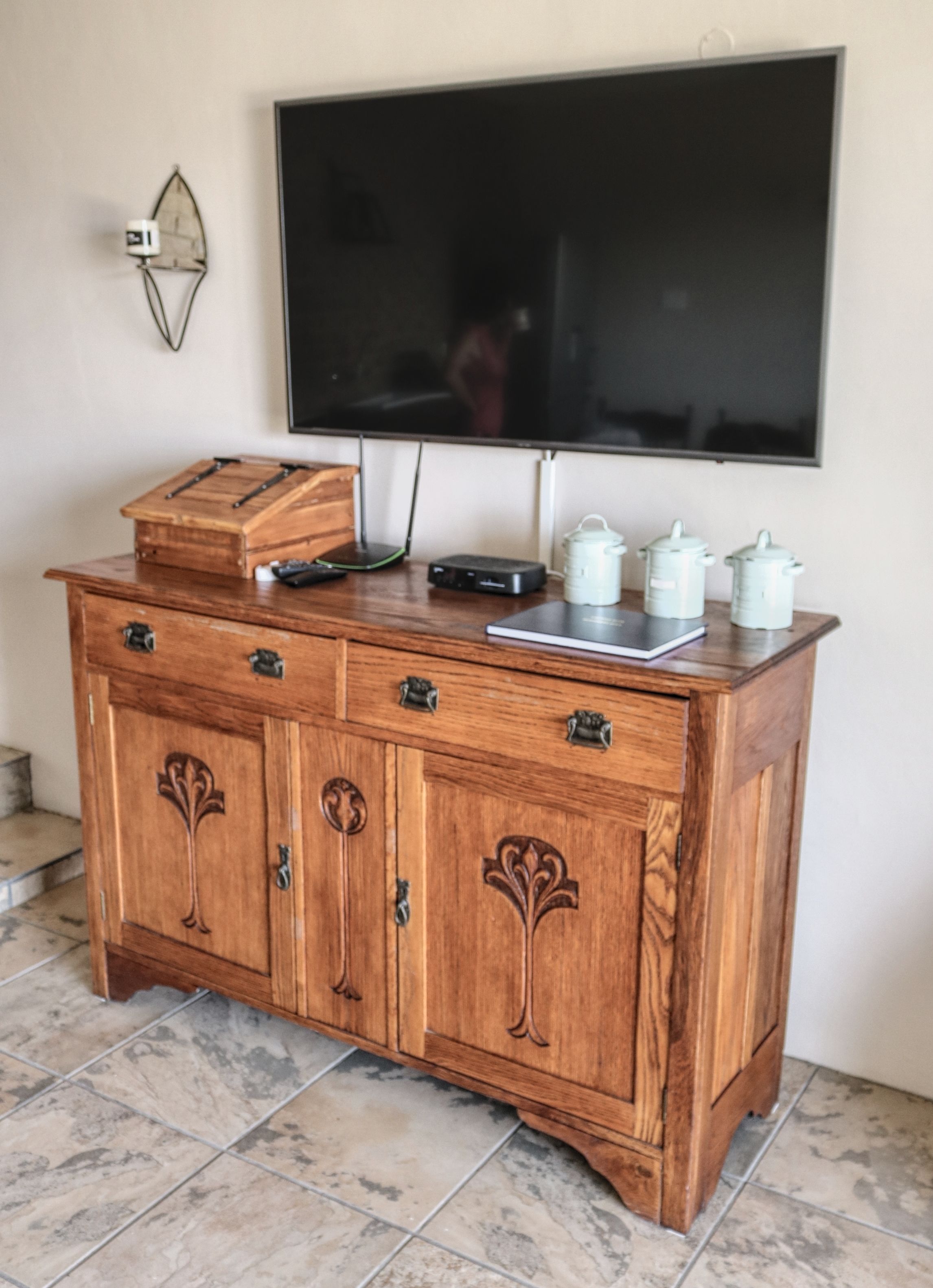A wooden cabinet with drawers and a flat-screen TV mounted on the wall above it.
