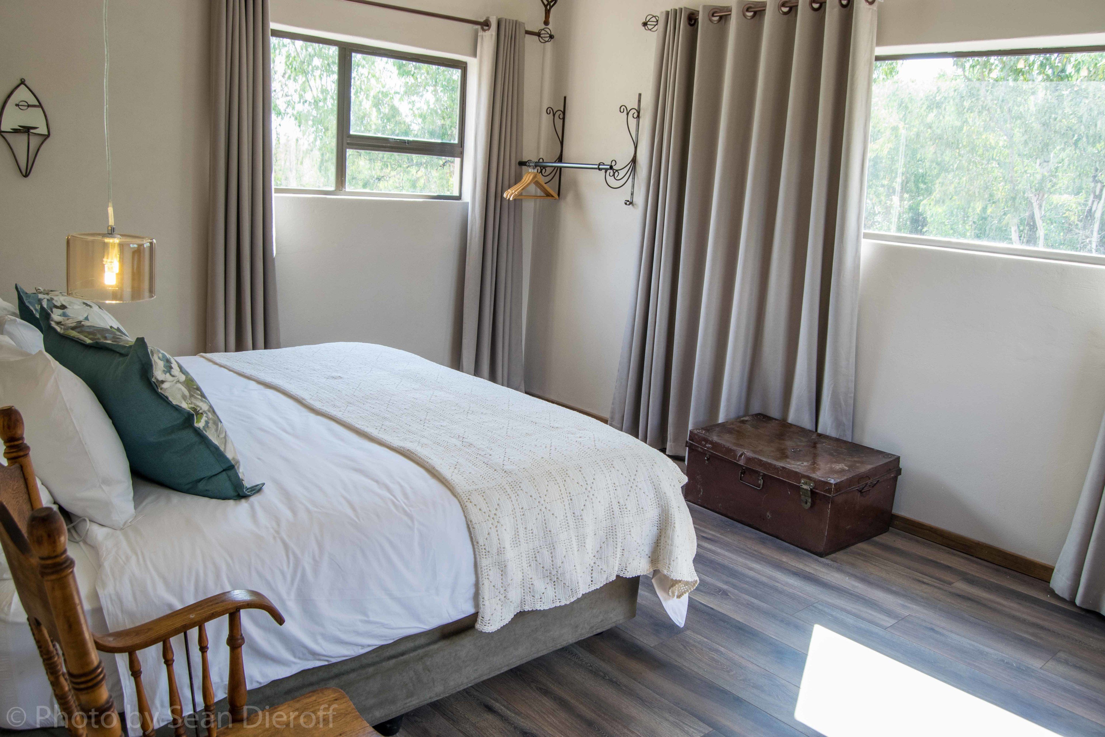 A neatly made bed with a wooden headboard, a bedside table, and a hanging light fixture.