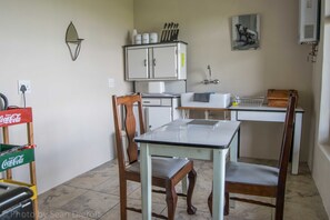Compact kitchen area with a microwave, sink, and dining table for two.