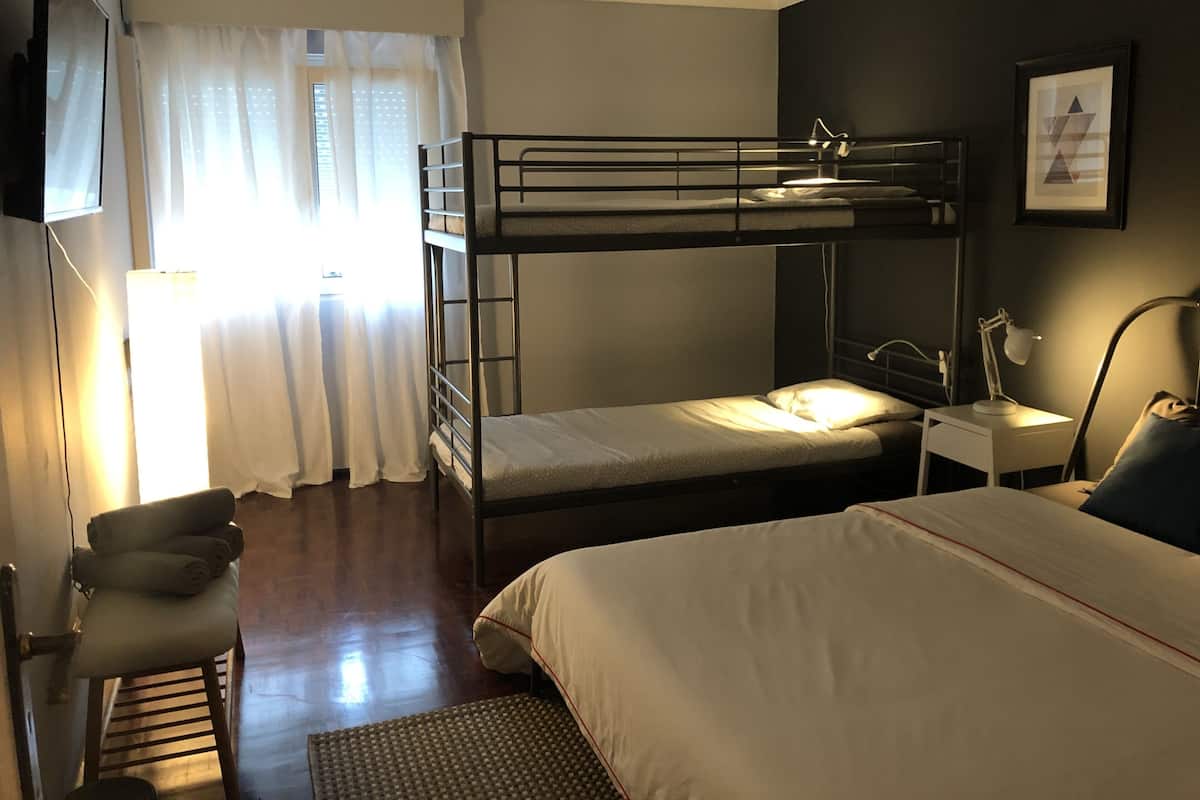 Een slaapkamer met een stapelbed, bureau, stoel en lamp.