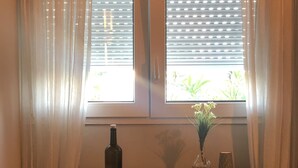 Et værelse med et skrivebord, en stol, en flaske og en vase med blomster.