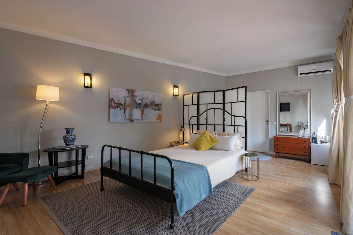 Een slaapkamer met een bed, nachtkastjes, een lamp, een dressoir en een spiegel.