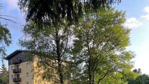 A courtyard with outdoor seating, a building with balconies, and a large heater. - Hotel Sayonara (Folgaria)
