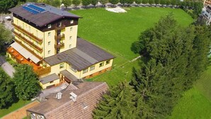 A multi-story building with a central tower, surrounded by lush greenery and a well-maintained lawn. - Hotel Sayonara (Folgaria)