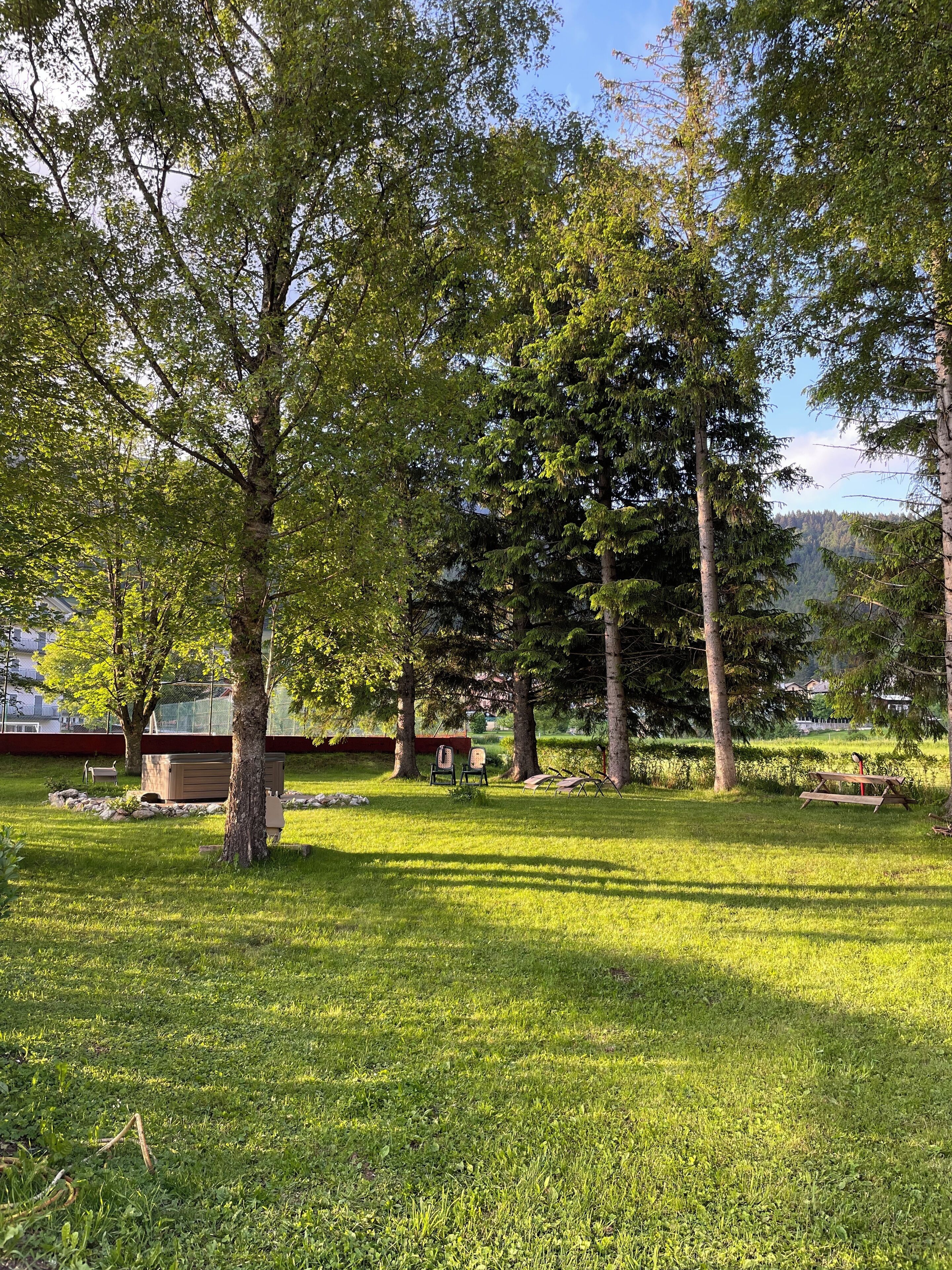A park with picnic tables, benches, and a playground.