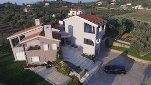 A modern two-story house with a sloped roof, a driveway, and a car parked in the front. - Villa Konstantina (Nafplio)