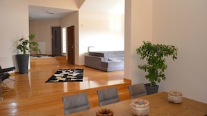 A modern living room with a grey sofa, wooden flooring, and a dining area with a table and chairs. - Villa Konstantina (Nafplio)