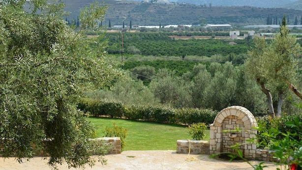 A stone archway leading to a paved area with a view of a lush garden and distant hills. - Villa Konstantina (Nafplio)