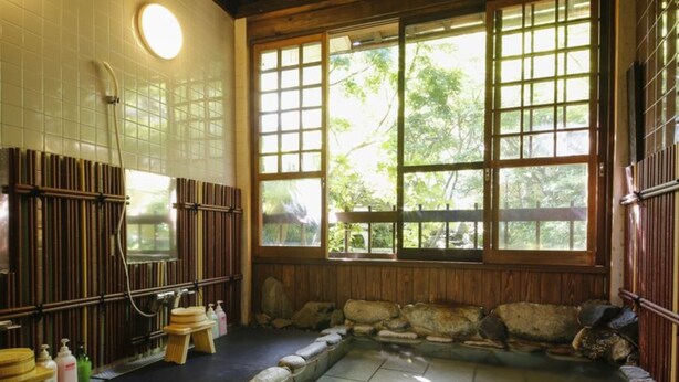 A traditional Japanese onsen with a stone bath, wooden walls, and large windows. - Kinosaki Onsen Ryokan Oyado Hakusan (Toyooka)