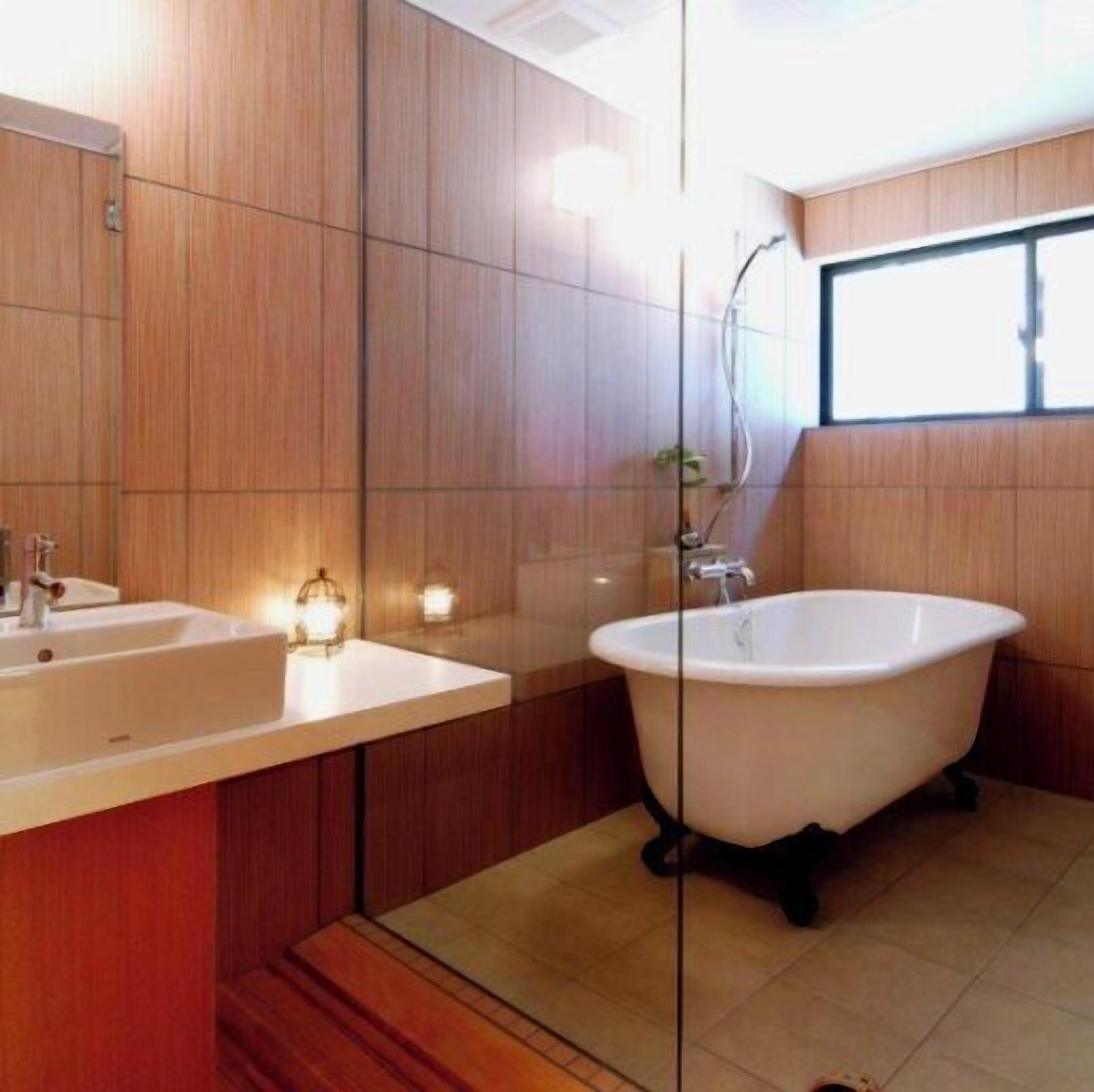 Un baño moderno con paneles de madera, una bañera independiente y un espejo grande.